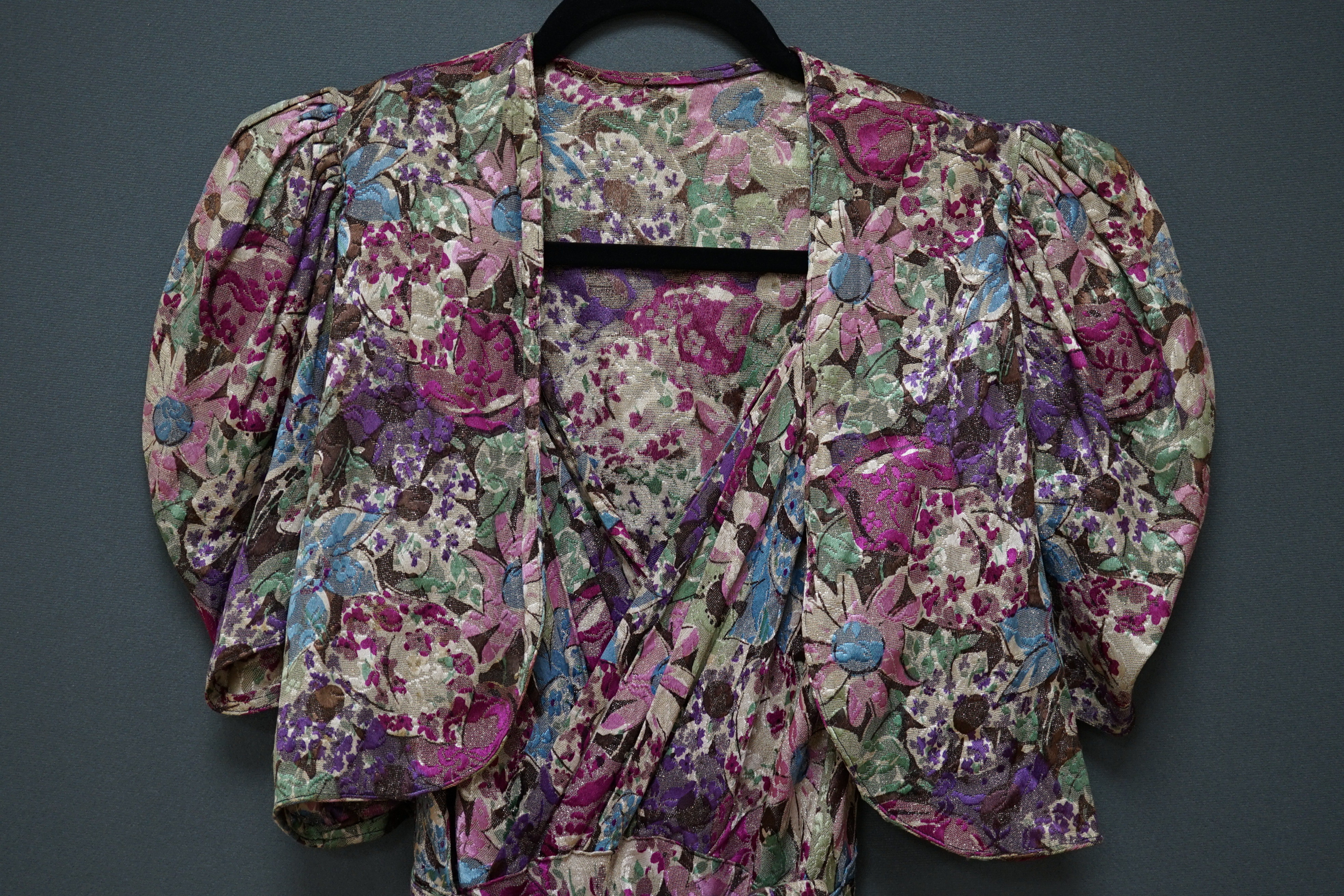 An early 1940’s floral lurex evening dress and bolero, handmade brightly coloured floral lurex, bias cut, with a cross over plunging bodice, half belt and matching bolero, 40cm front bodice arm to arm. Condition - the co